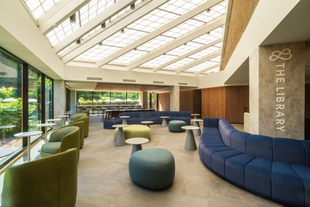 Light filled space with green chairs, a blue couch and tables and chairs